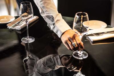 Un barman verse un liquide sombre d'une petite bouteille dans un verre à cocktail rempli d'une boisson mousseuse.