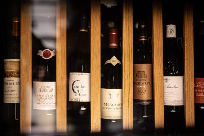 Un barman verse un liquide sombre d'une petite bouteille dans un verre à cocktail rempli d'une boisson mousseuse.