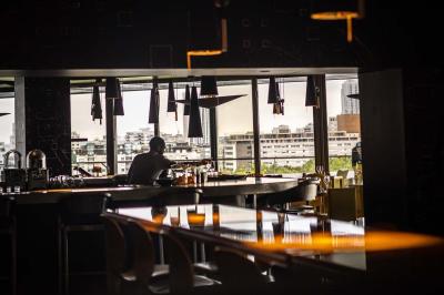 Un barman verse un liquide sombre d'une petite bouteille dans un verre à cocktail rempli d'une boisson mousseuse.