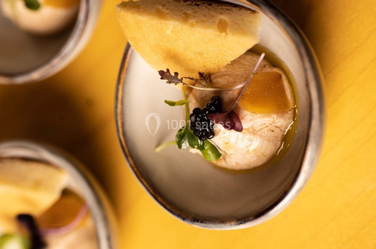 Une assiette contenant une boule de crème glacée, des fruits, des herbes fraîches et une tranche de pain.