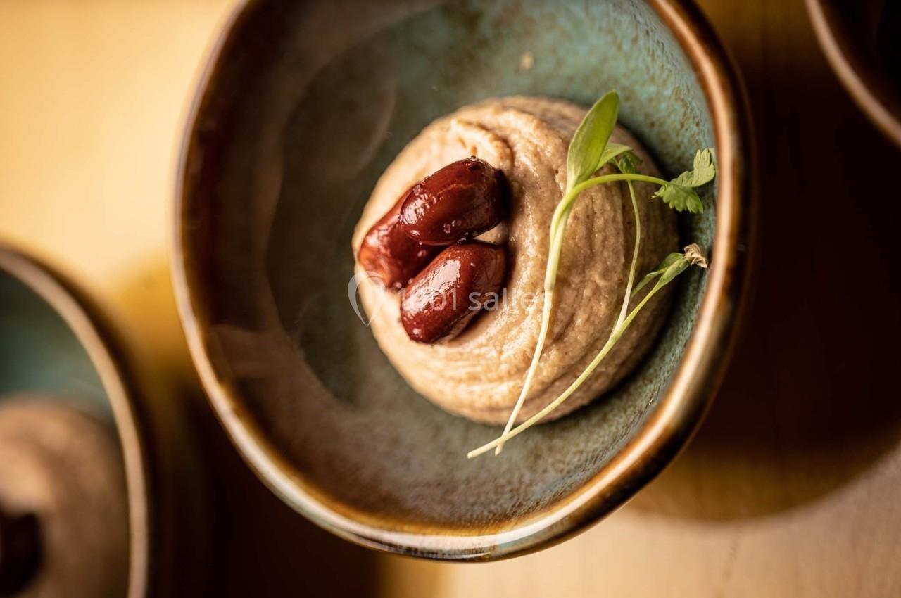 Purée crémeuse servie dans un bol en céramique, garnie de deux olives et d'une herbe fraîche.