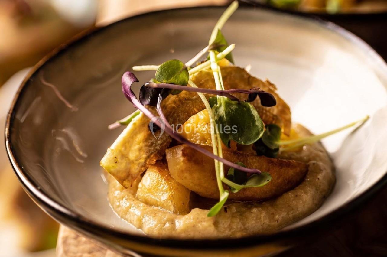 Assiette de légumes rôtis sur une purée crémeuse, garnie de jeunes pousses.