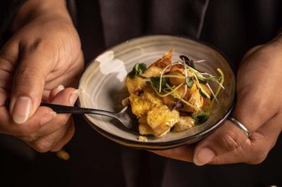 Un barman verse un liquide sombre d'une petite bouteille dans un verre à cocktail rempli d'une boisson mousseuse.