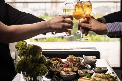 Un barman verse un liquide sombre d'une petite bouteille dans un verre à cocktail rempli d'une boisson mousseuse.