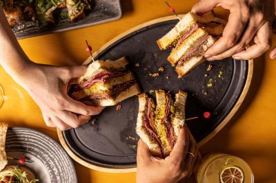 Un barman verse un liquide sombre d'une petite bouteille dans un verre à cocktail rempli d'une boisson mousseuse.