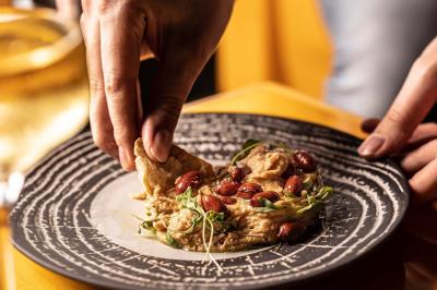 Un barman verse un liquide sombre d'une petite bouteille dans un verre à cocktail rempli d'une boisson mousseuse.