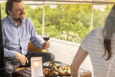 Un barman verse un liquide sombre d'une petite bouteille dans un verre à cocktail rempli d'une boisson mousseuse.
