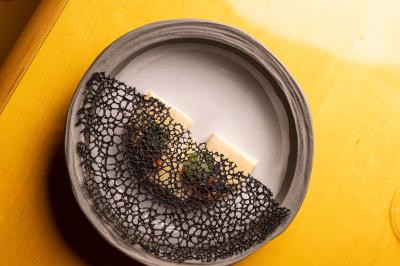 Un barman verse un liquide sombre d'une petite bouteille dans un verre à cocktail rempli d'une boisson mousseuse.