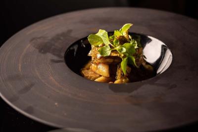 Un barman verse un liquide sombre d'une petite bouteille dans un verre à cocktail rempli d'une boisson mousseuse.