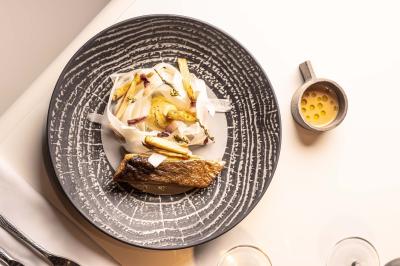 Un barman verse un liquide sombre d'une petite bouteille dans un verre à cocktail rempli d'une boisson mousseuse.