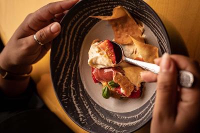Un barman verse un liquide sombre d'une petite bouteille dans un verre à cocktail rempli d'une boisson mousseuse.