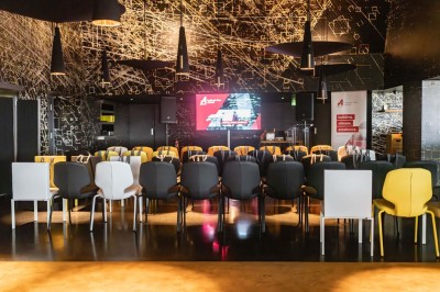 Un barman verse un liquide sombre d'une petite bouteille dans un verre à cocktail rempli d'une boisson mousseuse.