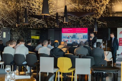 Un barman verse un liquide sombre d'une petite bouteille dans un verre à cocktail rempli d'une boisson mousseuse.