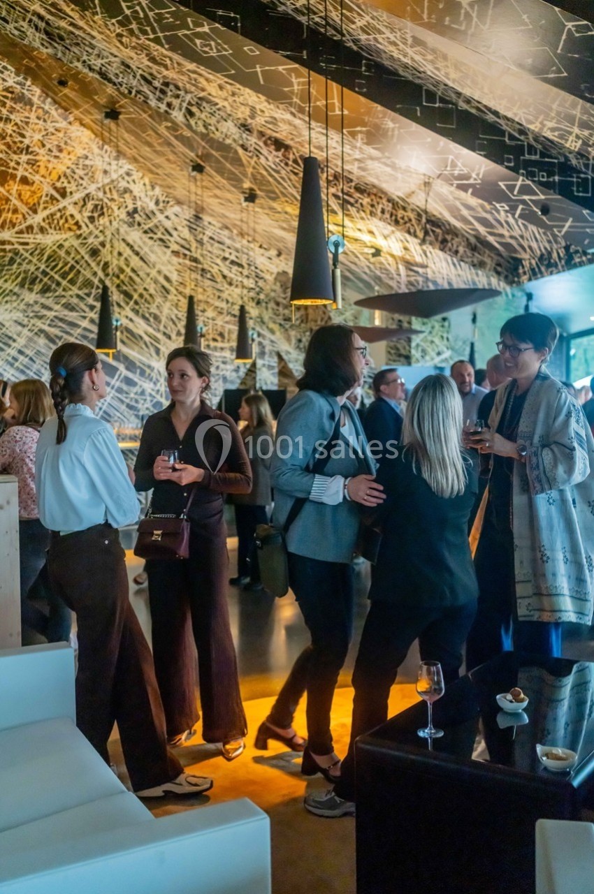Groupe de personnes discutant debout dans un espace intérieur moderne avec un éclairage tamisé.