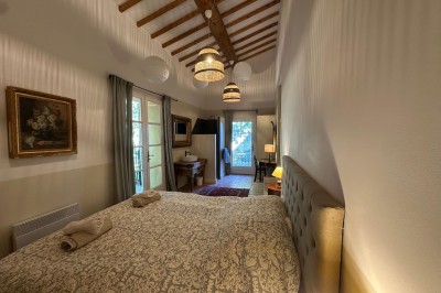 Miniature Location salle Rognes (Bouches-du-Rhône) - Château Barbebelle #36 Chambre lumineuse avec lit double, poutres apparentes, décoration classique et vue sur un balcon arboré.