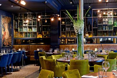 Salle de réunion avec tables dressées, chaises noires, murs en pierre et éclairage tamisé.