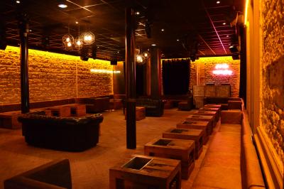 Salle de réunion avec tables dressées, chaises noires, murs en pierre et éclairage tamisé.