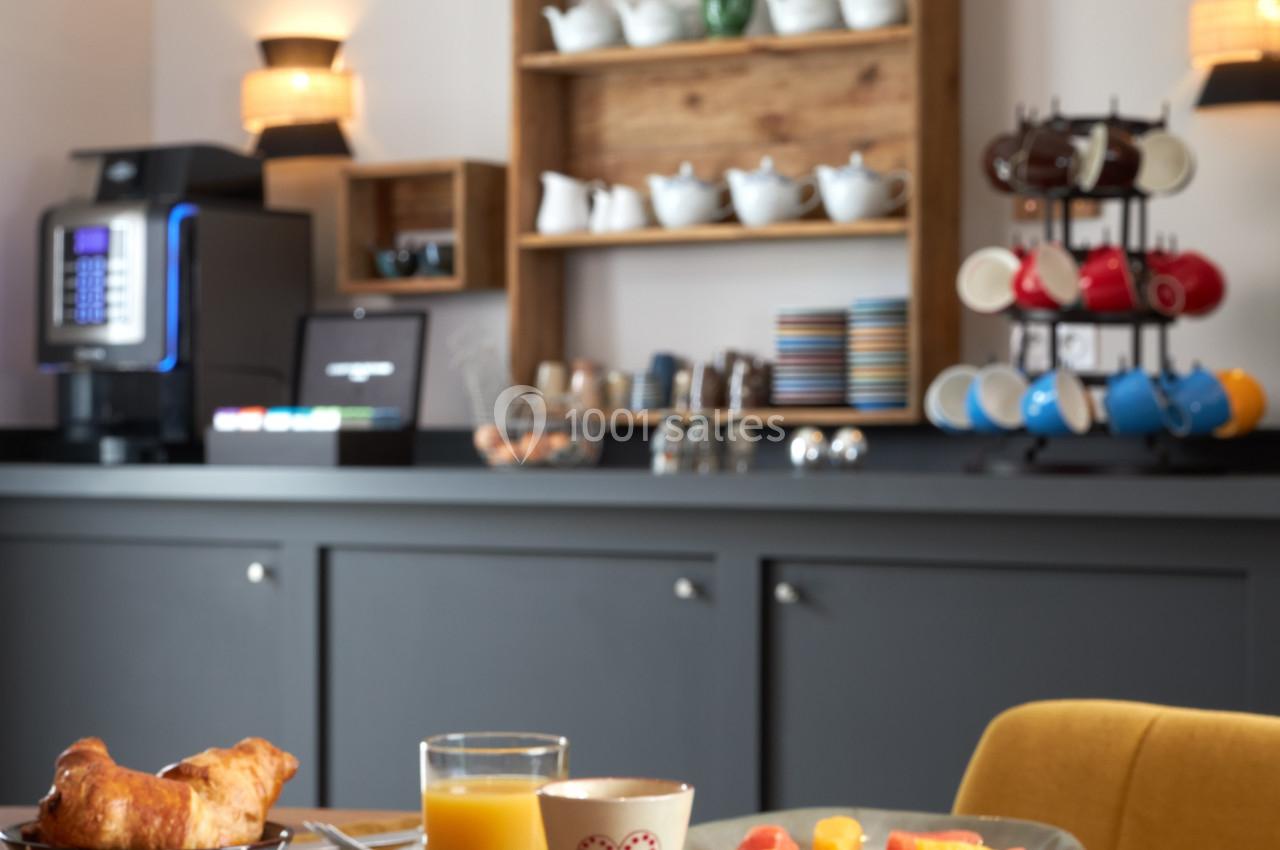 Petit-déjeuner servi avec charcuterie, fromage, fruits, viennoiseries, œuf à la coque et boissons, dans une salle lumineuse.