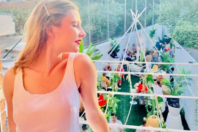 Salle de bain moderne avec lavabo double, miroir, toilettes grises et étagères décorées de plantes et flacons.