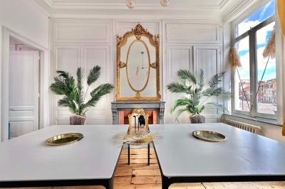 Salle de bain moderne avec lavabo double, miroir, toilettes grises et étagères décorées de plantes et flacons.