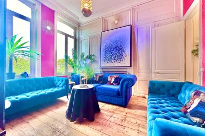 Salle de bain moderne avec lavabo double, miroir, toilettes grises et étagères décorées de plantes et flacons.