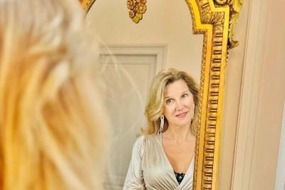 Salle de bain moderne avec lavabo double, miroir, toilettes grises et étagères décorées de plantes et flacons.