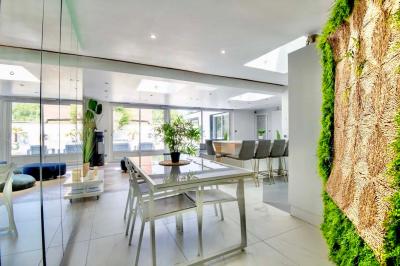 Salle de bain moderne avec lavabo double, miroir, toilettes grises et étagères décorées de plantes et flacons.