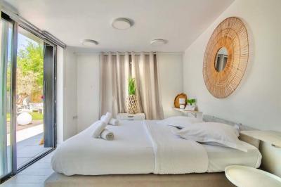 Salle de bain moderne avec lavabo double, miroir, toilettes grises et étagères décorées de plantes et flacons.