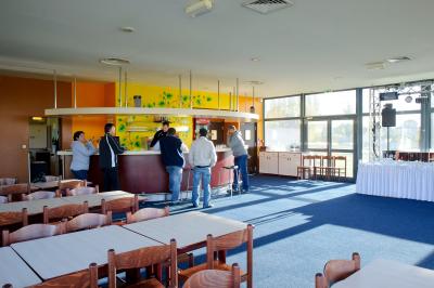 Vue d'un terrain de golf avec des joueurs sur le green, entouré d'arbres et d'un bâtiment en arrière-plan.