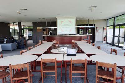 Vue d'un terrain de golf avec des joueurs sur le green, entouré d'arbres et d'un bâtiment en arrière-plan.