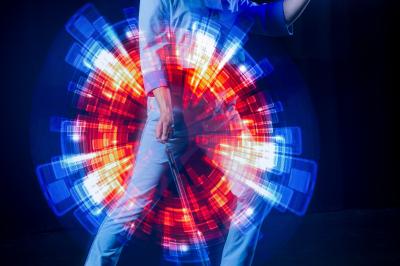 Un jongleur manipule des bâtons rouges dans une galerie lumineuse avec une verrière en arrière-plan.