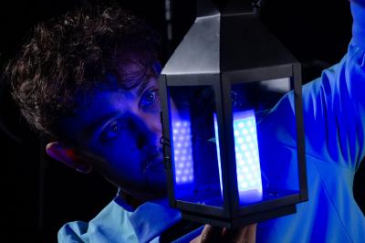 Un jongleur manipule des bâtons rouges dans une galerie lumineuse avec une verrière en arrière-plan.