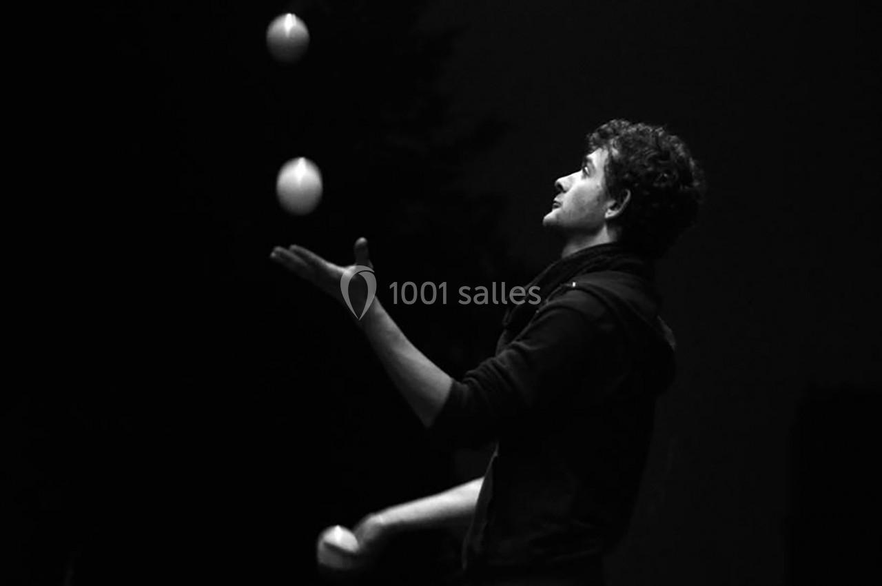Un homme jongle avec trois balles dans un environnement sombre.