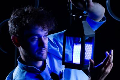 Un jongleur réalise une performance avec des bâtons rouges dans une galerie lumineuse bordée de colonnes.