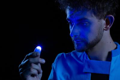 Un jongleur réalise une performance avec des bâtons rouges dans une galerie lumineuse bordée de colonnes.