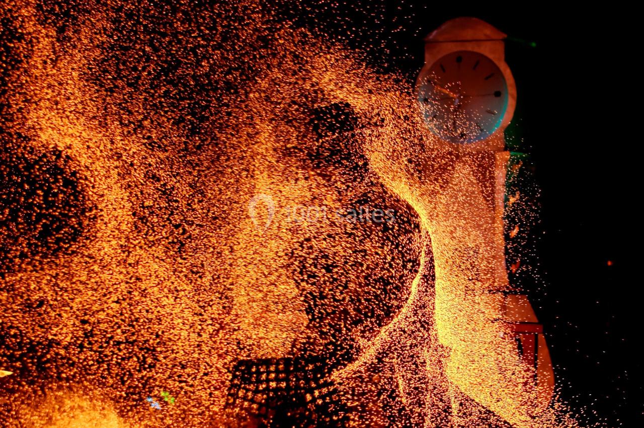 Étincelles orange vives s'élèvent dans l'obscurité devant une horloge blanche illuminée.