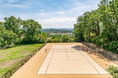 Miniature Location salle Aix-en-Provence (Bouches-du-Rhône) - La Migranière #6 Terrain de tennis en plein air entouré d'arbres et de verdure, avec une vue dégagée sur l'horizon.