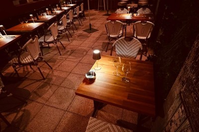 Salle de restaurant lumineuse avec tables en bois, chaises vertes, décorations végétales et comptoir en arrière-plan.