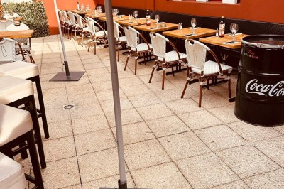 Salle de restaurant lumineuse avec tables en bois, chaises vertes, décorations végétales et comptoir en arrière-plan.