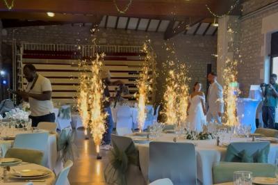 Mariés entrant dans une salle de réception décorée, entourés de fontaines lumineuses et de tables dressées.