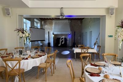 Salle de réception décorée avec des tables dressées, un projecteur, un écran et une piste de danse éclairée.