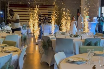 Salle de réception décorée avec des tables élégantes, des chaises ornées de nœuds verts et des fontaines lumineuses en…