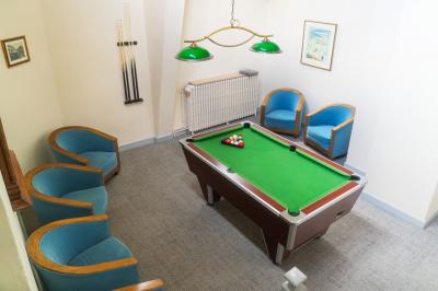 Statue de sphinx en pierre posée sur un socle, entourée de végétation et d'une haie dans un jardin.