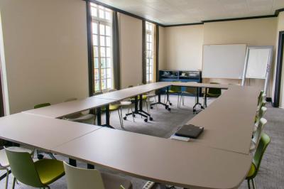 Statue de sphinx en pierre posée sur un socle, entourée de verdure dans un jardin.