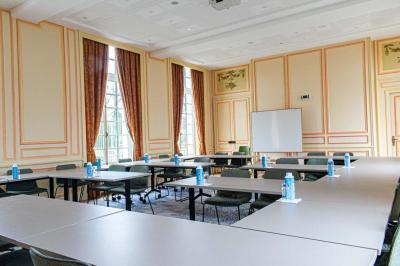 Statue de sphinx en pierre posée sur un socle, entourée de verdure dans un jardin.