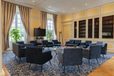 Statue de sphinx en pierre posée sur un socle, entourée de verdure dans un jardin.