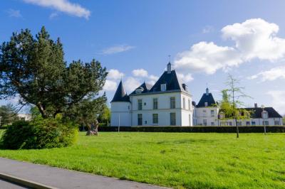 Statue de sphinx en pierre posée sur un socle, entourée de verdure dans un jardin.