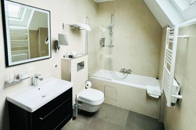 Statue de sphinx en pierre posée sur un socle, entourée de verdure dans un jardin.