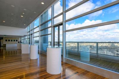 Vue d'une terrasse végétalisée surplombant Paris avec la Tour Eiffel visible à l'horizon sous un ciel bleu.