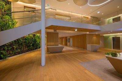 Vue d'une terrasse végétalisée surplombant Paris avec la Tour Eiffel visible à l'horizon sous un ciel bleu.